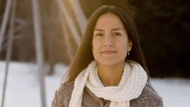 Une femme souriante pose à l'extérieure avec de la neige en arrière-plan.