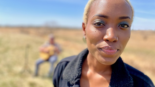 L'auteure-compositrice-interprète Nyenimana se prépare à l'enregistrement d'une chanson dans un champ tout près de Regina. Elle est accompagnée à la guitare par Dave Lawlor.