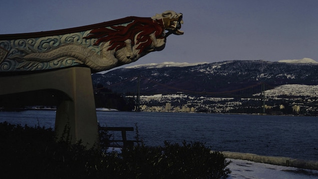Le monument SS Empress of Japan Figurehead sur le bord du Seawall du parc Stanley, pointant vers la mer et les montagnes.