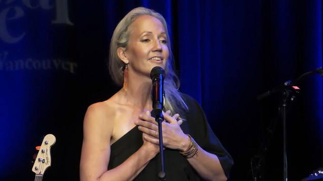 La musicienne Pascale Goodrich-Black derrière un micro, les mains croisées sur la poitrine.