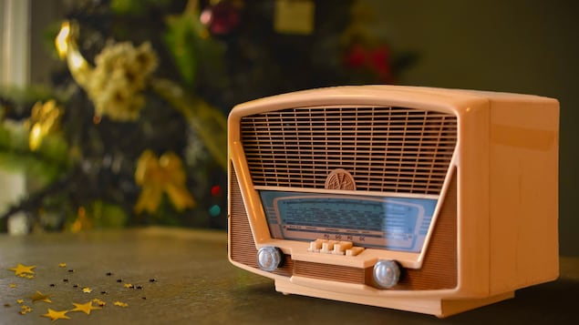 Une radio des années 60 repose sur une table de bois devant un sapin de Noël.