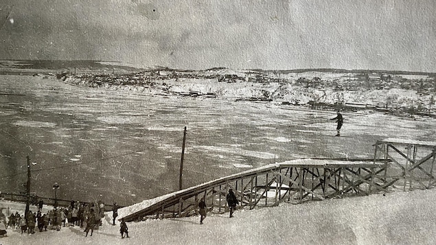 Une rampe de saut à ski dans les années 1920. On voit un skieur s'élancer. Il semble hésitant. La journée d'hiver est belle, derrière, on voit la glace sur le fleuve, la côte de Lévis, et une petite foule de spectateurs en bas de la rample. 
