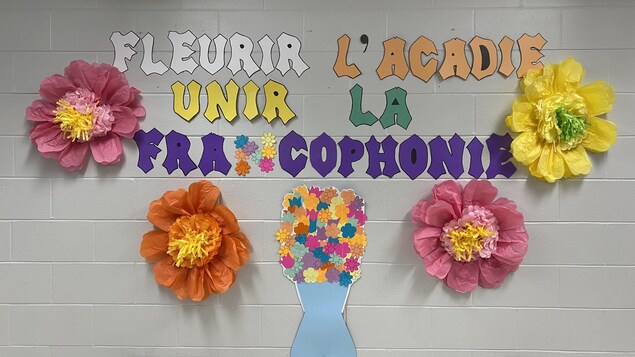 Le slogan écrit sur un mur d'école, avec des décorations de fleurs en papier.