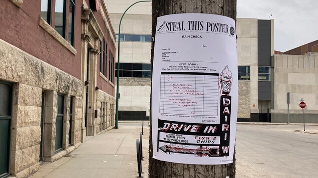 Une affiche blanche du Martha Street Studio sur un poteau brun, dans une rue de Winnipeg.