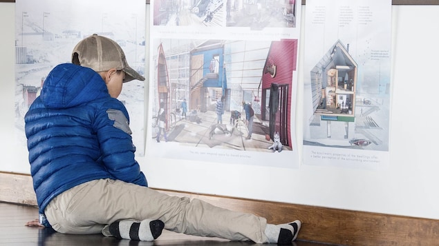 Un garçon regarde une photo avec des rendus 3D d'architecture. 