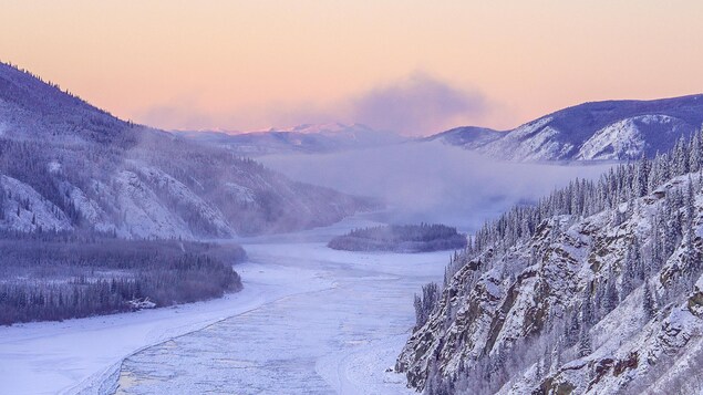 Un fleuve partiellement gelé entouré de montagnes, au Yukon