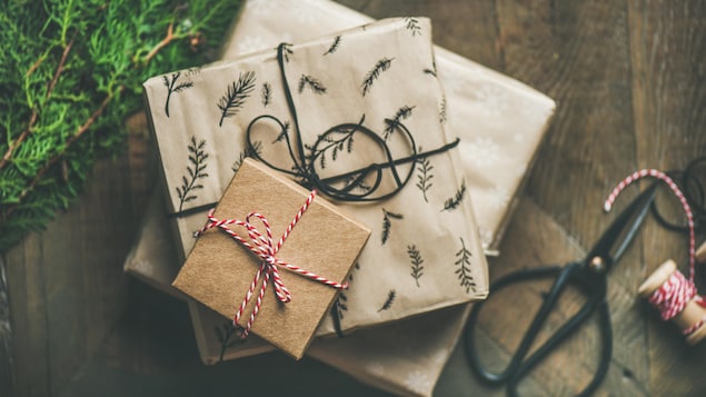 Des cadeaux emballés dans du papier brun décoré sur le bord d'un sapin. 