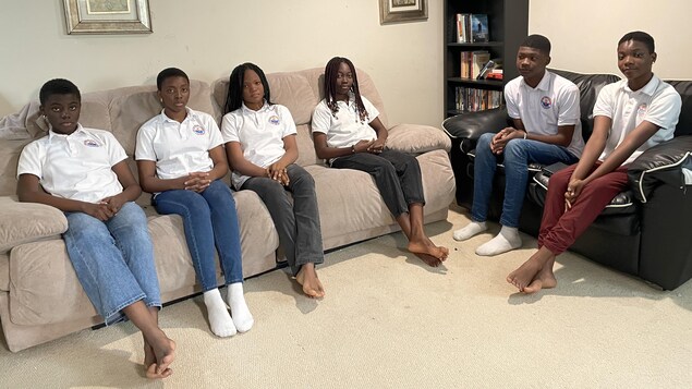 Six jeunes adolescents assis sur un canapé. 