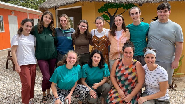 Dix étudiants et étudiantes et deux accompagnatrices  souriants devant une maison au Sénégal.
