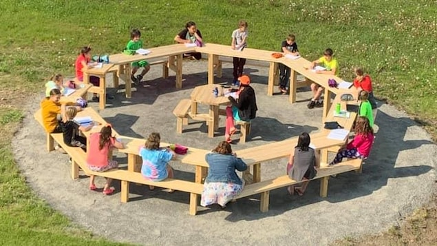 Des enfants autour d'une grande table à pique-nique.
