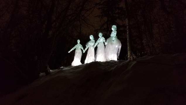 Sculptures sur glace illuminées dans la nuit dans une forêt.