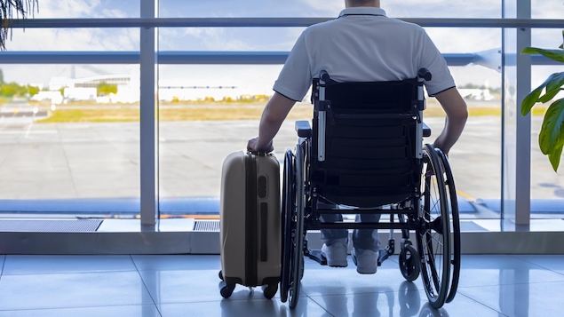Un homme en chaise roulante avec son bagage à l'aéroport.