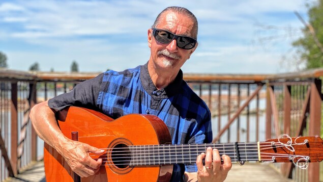 André Thibault pose avec sa guitare.