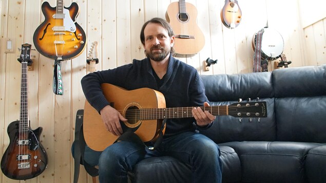 David Siddall est assis sur un sofa, guitare en main