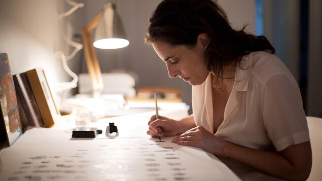 Une femme assise à une table en train de dessiner.