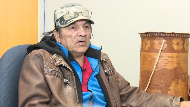 Un homme autochtone avec un manteau brun en entrevue.