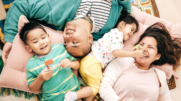 Famille entrain de rire, allongée sur des coussins