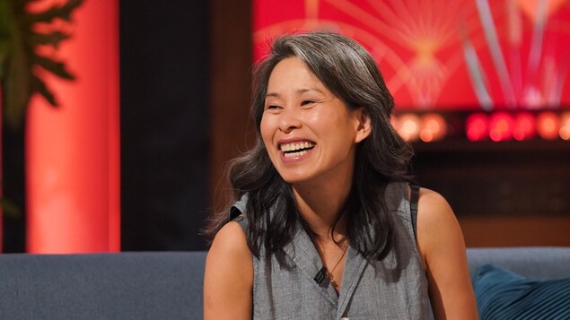 L'autrice sourit, assise sur un divan dans un décor de télé. 