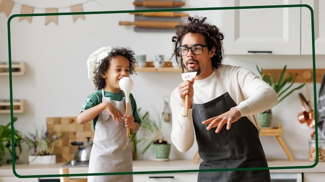 Un père et son fils cuisinent en chantant.