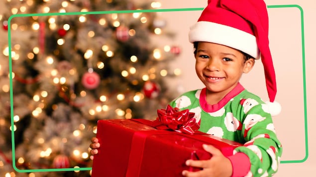 Un enfant avec un bonnet rouge et blanc est heureux de recevoir un cadeau de Noël.