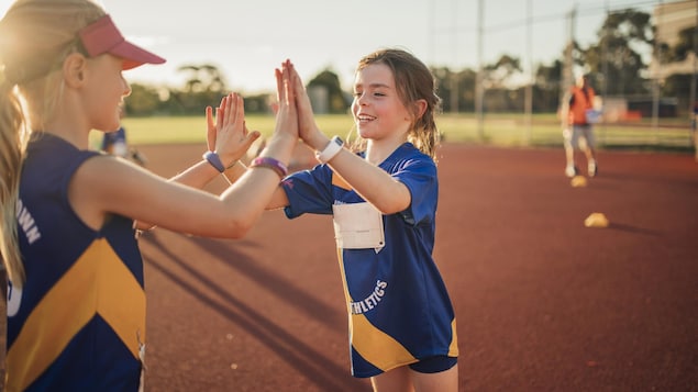 Deux petites filles se font un high five sur le terrain de sport