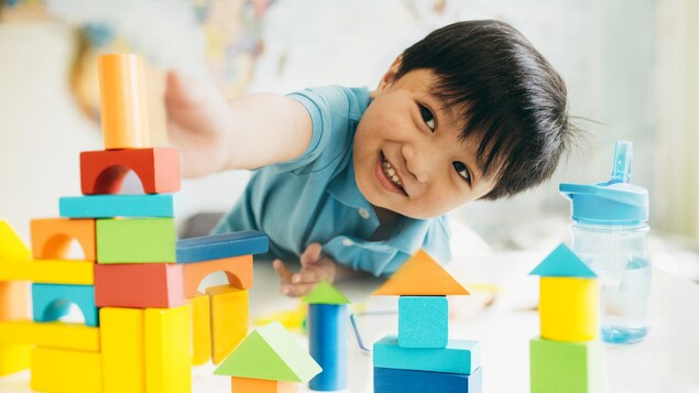 Le petit garçon est d'origine asiatique, il joue avec des cubes à la garderie