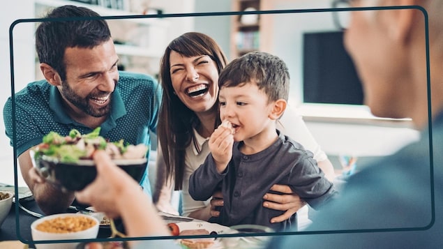 Papa, maman, mamie et le petit garçon rient à table. 
