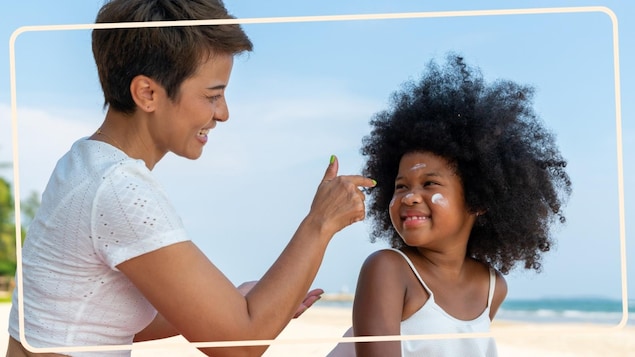 Une mère met de la crème solaire à sa fille.