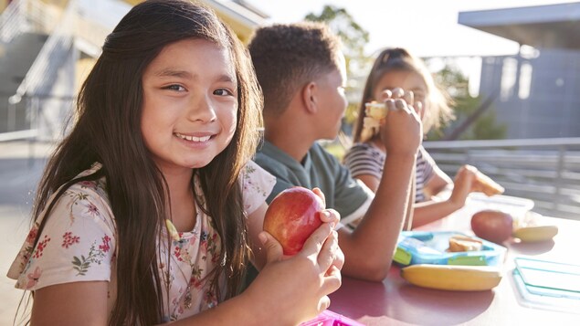 Une jeune fille d'environ 8 ans tient une pomme