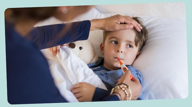 Un petit garçon est malade dans son lit, sa maman prend sa température. 