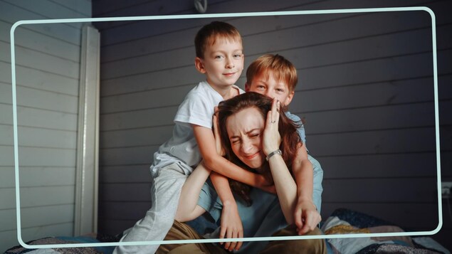 Une maman fatiguée est entourée par ses deux jeunes enfants. 