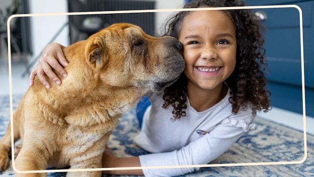 Une fillette et un chien se font un câlin. 
