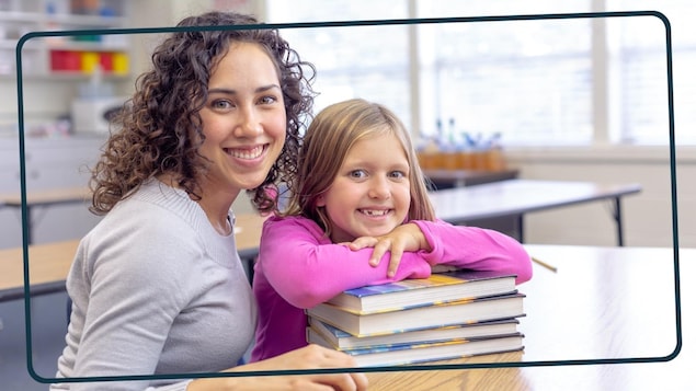 Une enseignante pose à côté d'une jeune élève, tout sourire. 