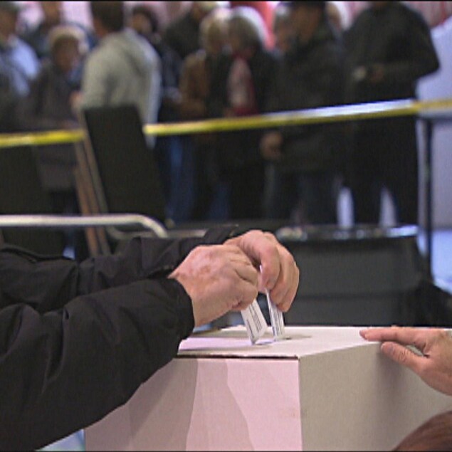 Un homme met son bulletin de vote dans une boîte.