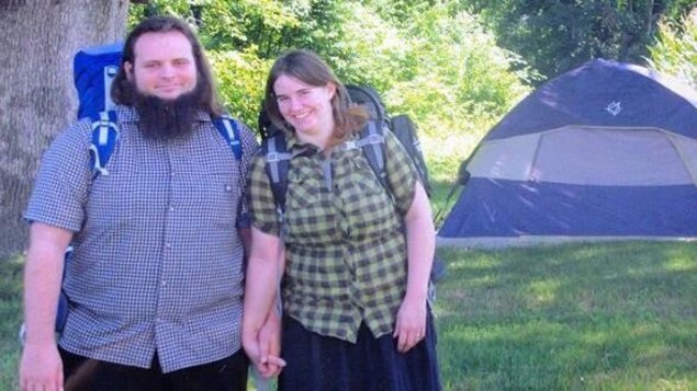 Photo de Caitlan Coleman et de Joshua Boyle qui se tiennent la main et qui portent des sacs à dos.