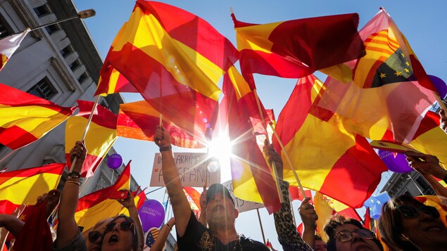 Des gens brandissent des drapeaux de l'Espagne lors d'une manifestation contre l'indépendance, à Barcelone.