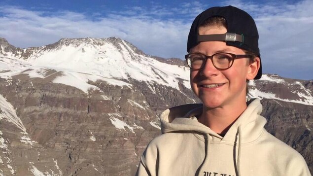 Gustave Bouchard, 15 ans, a lancé une pétition pour l'aménagement de pistes de vélo de montagne au Mont-Orford. On le voit ici posé devant des montagnes, au Chili.