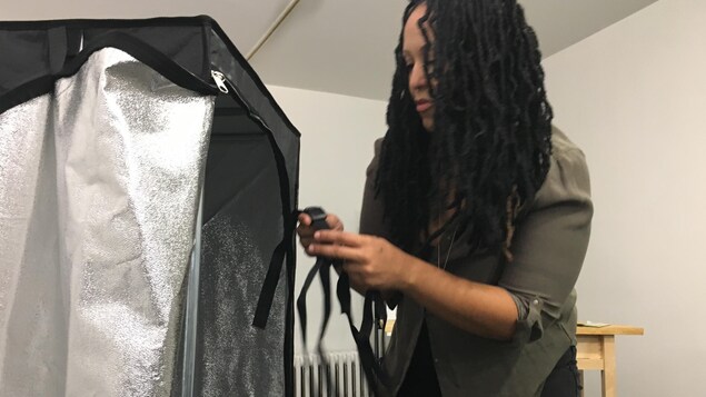 Photo d'une femme qui serre la sangle d'une tente hydroponique.