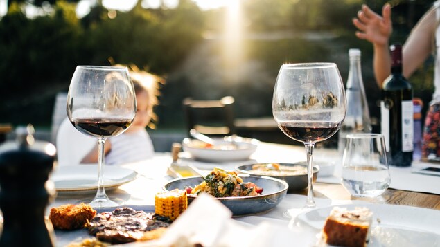 Des plats et des coupes de vin rouge sont disposés sur une table. 