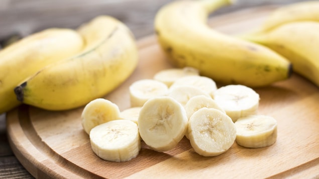 Une banane coupée en morceaux sur une planche.