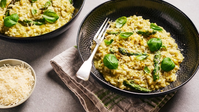 Du risotto aux asperge garni de feuilles de basilic dans un bol.