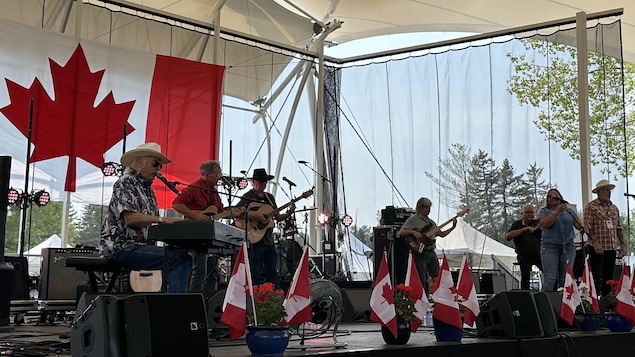 Un groupe de musiciens sur scène avec des drapeaux canadiens. 