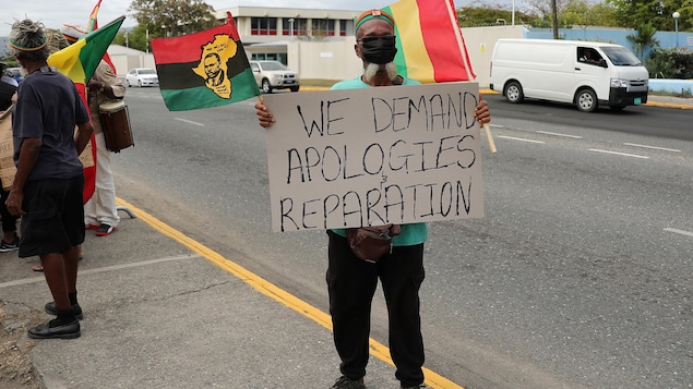 Un manifestante sostiene un cartel en Kingston durante una manifestación para exigir que la monarquía británica pague reparaciones por la esclavitud, antes de la llegada a Jamaica del duque y la duquesa de Cambridge como parte de su gira por el Caribe. Jamaica 22 de marzo de 2022. 