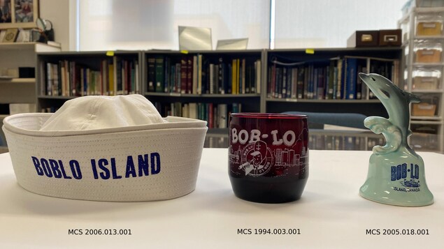 Un chapeau, un verre, et une cloche à l'effigie d'un dauphin, conservés dans un centre d'archives.