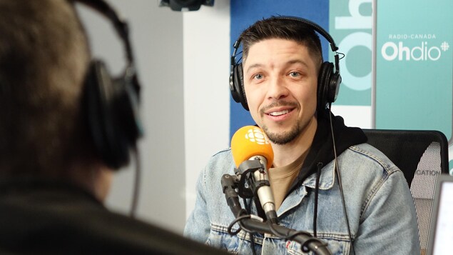 Un comédien parle dans un micro dans un studio radio. 