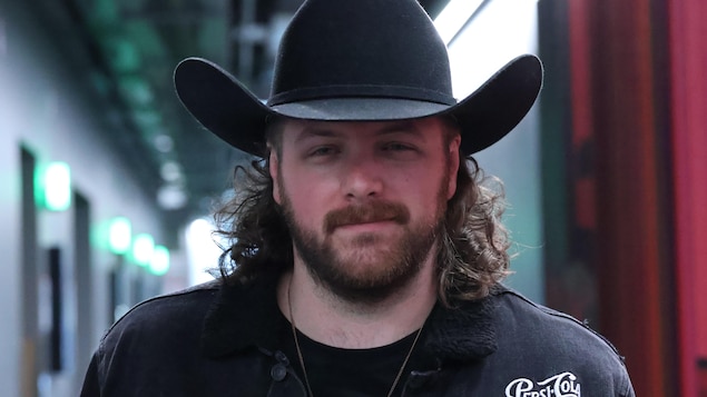Il pose devant la caméra avec un chapeau de cowboy