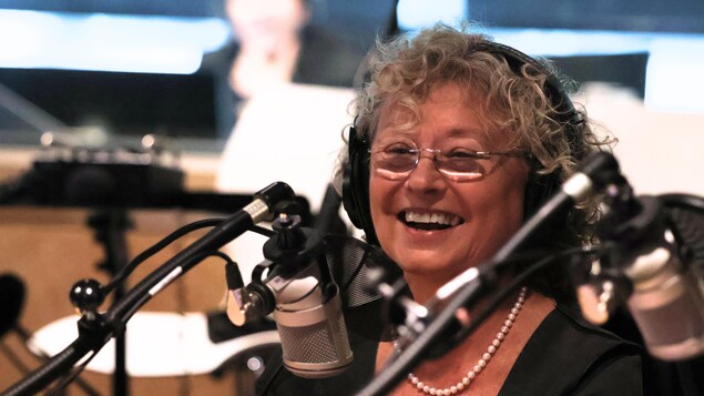 Elle sourit devant un micro.