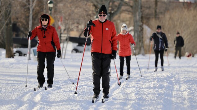 Des personnes font du ski de fond dans un parc situé dans un centre ville. 