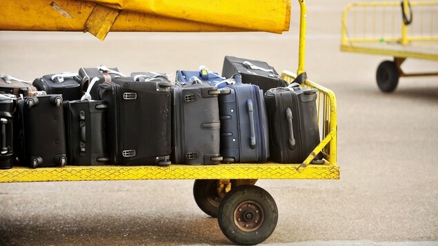 Un chariot rempli de valises sur le tarmac d'un aéroport. 