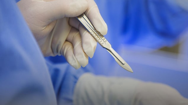 Un chirurgien manipule un scalpel.